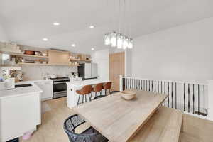Dining area with light wood finished floors, vaulted ceiling, and recessed lighting