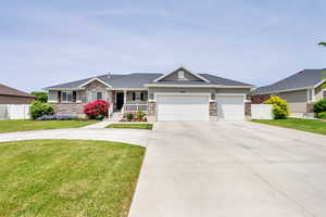 Ranch-style home featuring stone siding, concrete driveway, covered porch, a garage, and stucco siding
