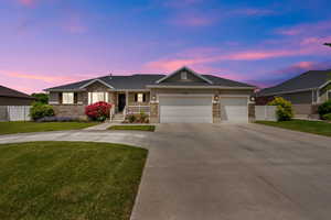 Single story home featuring stone siding, concrete driveway, an attached garage, and covered porch