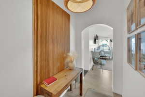 Corridor with arched walkways, wood finished floors, a high ceiling, and baseboards