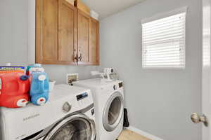 Laundry room featuring washer and dryer, cabinet space, and baseboards