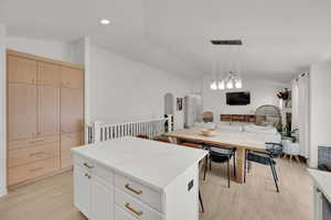 Kitchen featuring lofted ceiling, open floor plan, light wood-style floors, arched walkways, and a kitchen island