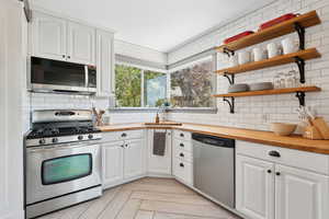 Updated kitchen featuring a gas stove; butcher block counter tops, and subway tile backsplash. Stainless steel appliances are included.