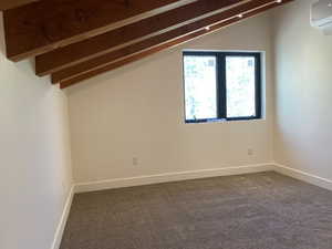 Additional living space with a wall mounted air conditioner, carpet floors, and baseboards