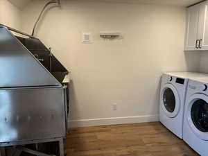 Washroom featuring cabinet space, washer and dryer, light wood-style floors, and baseboards