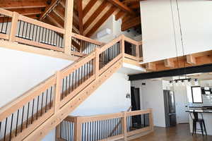 Stairs with high vaulted ceiling, beam ceiling, and wood finished floors