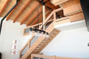 Stairs featuring a high ceiling and wood ceiling with exposed beams