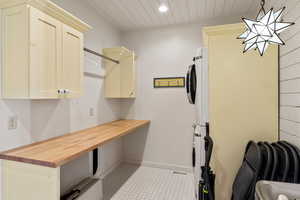 Laundry area with stacked washer / dryer, cabinet space, wood ceiling, recessed lighting, and baseboards