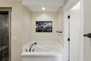 Bathroom with a garden tub, wood walls, and wooden ceiling with exposed beams
