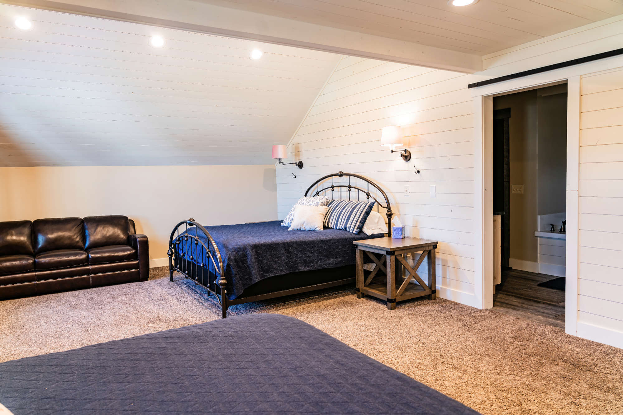 Carpeted bedroom with vaulted ceiling, wood walls, recessed lighting, baseboards, and ensuite bath