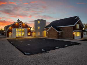 Back of property featuring a barn, uncovered parking, an outdoor structure, and a shingled roof