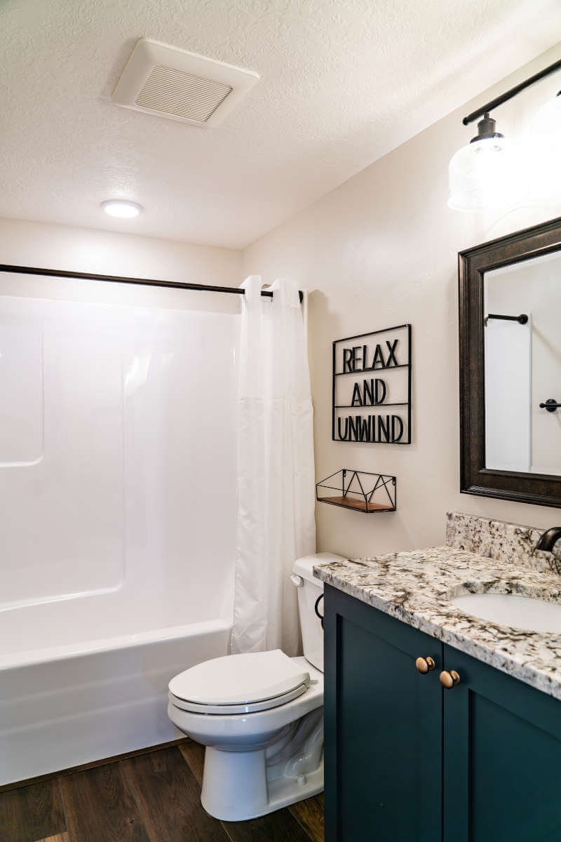Bathroom with vanity, toilet, shower / tub combo with curtain, wood finished floors, and a textured ceiling