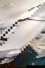 Bathroom with vanity, toilet, shower / tub combo with curtain, wood finished floors, and a textured ceiling