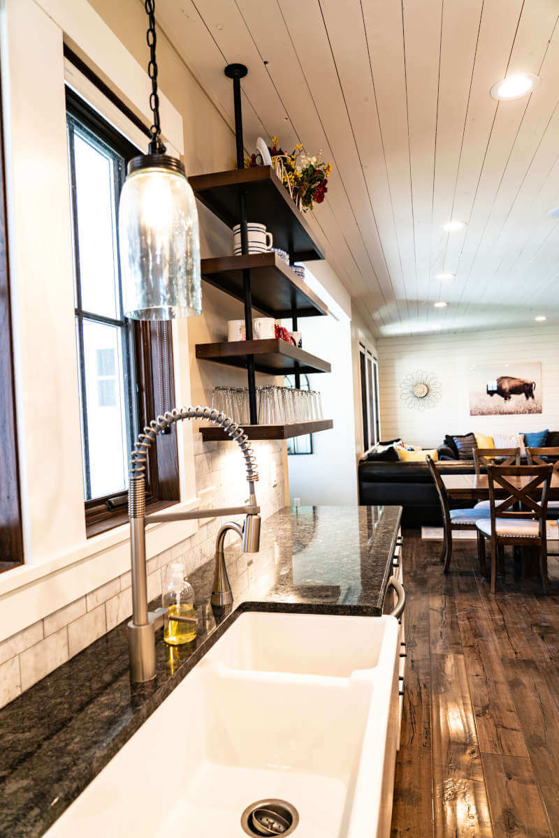 Kitchen with a sink, dark wood-style flooring, wood ceiling, open shelves, and tasteful backsplash