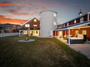 Back of property at dusk with an outdoor living space with a fire pit, a patio, metal roof, and a standing seam roof