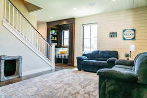 Living room with recessed lighting, wooden walls, wood finished floors, stairway, and baseboards