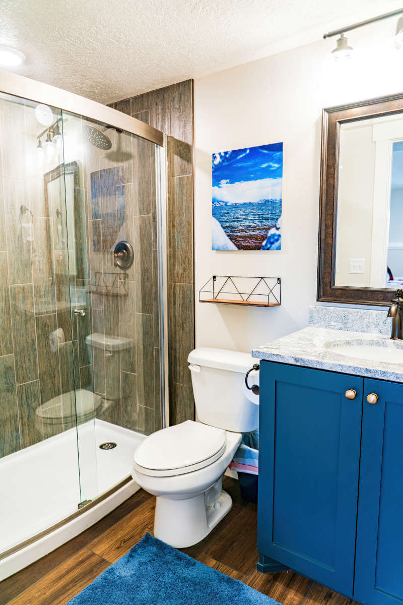 Full bathroom with vanity, toilet, a textured ceiling, a stall shower, and wood finished floors