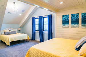 Bedroom featuring carpet, a chandelier, vaulted ceiling, wood walls, and recessed lighting