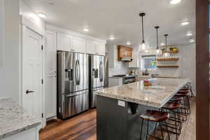 Kitchen featuring stainless steel appliances, dark wood-type flooring, a kitchen bar, white cabinets, and recessed lighting