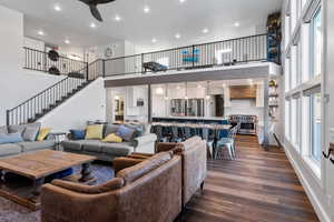 Living area with a towering ceiling, dark wood-style flooring, stairs, recessed lighting, and a ceiling fan