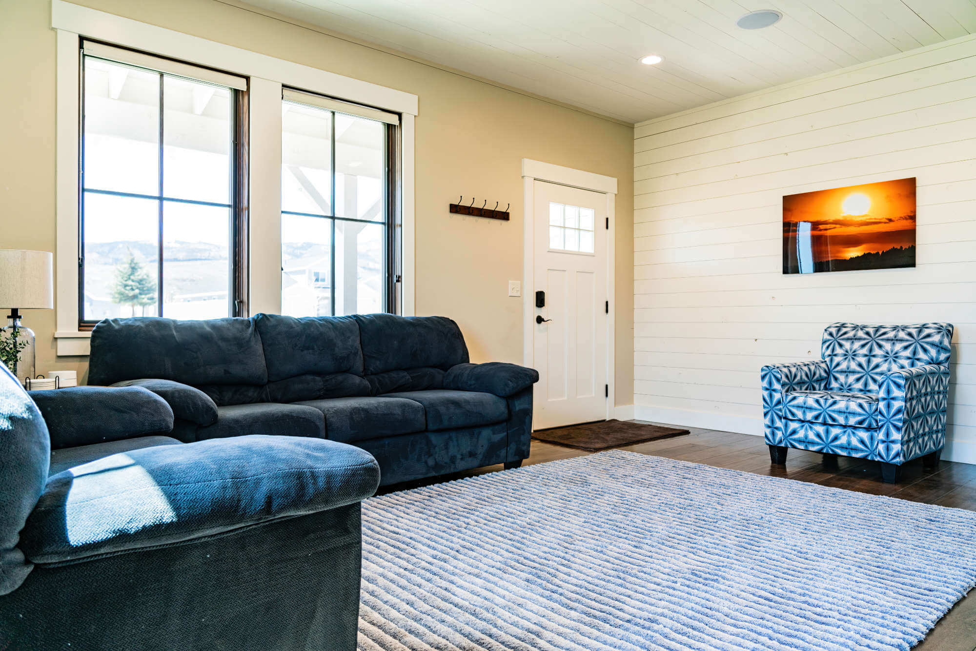 Living room with dark wood-style flooring, wooden walls, recessed lighting, and baseboards