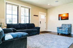 Living room with dark wood-style flooring, wooden walls, recessed lighting, and baseboards