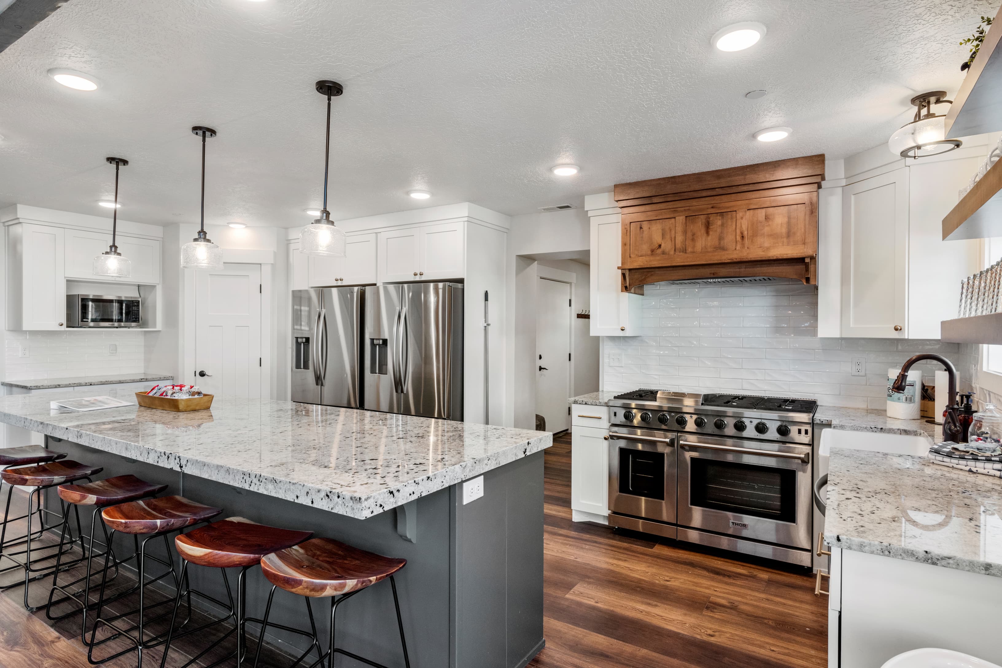 Kitchen with stainless steel appliances, white cabinets, decorative backsplash, light stone counters, and a textured ceiling