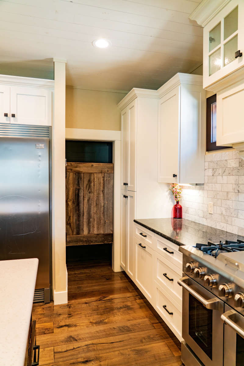 Kitchen with appliances with stainless steel finishes, white cabinetry, decorative backsplash, dark wood-style floors, and glass insert cabinets