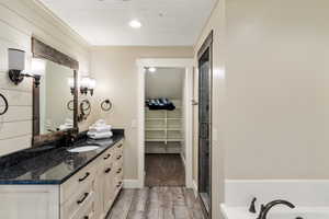 Full bathroom with wood finished floors, vanity, a walk in closet, and a shower with door
