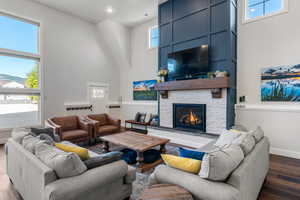 Living area featuring a towering ceiling, dark wood finished floors, a fireplace, and baseboards