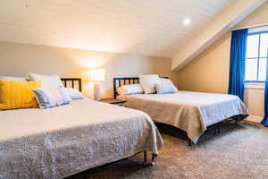 Carpeted bedroom featuring vaulted ceiling and wood ceiling