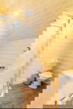 Bathroom featuring vaulted ceiling, a stall shower, wood finished floors, toilet, and vanity