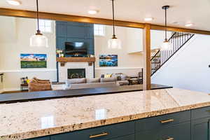 Kitchen featuring light stone countertops, a textured ceiling, decorative light fixtures, a fireplace, and baseboards