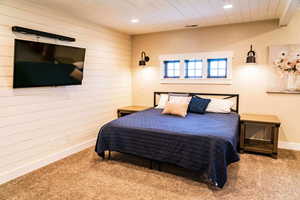 Carpeted bedroom featuring wood walls, recessed lighting, baseboards, and wood ceiling