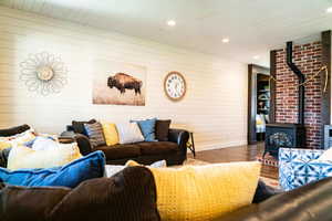 Living area with wood finished floors, a wood stove, wood walls, wooden ceiling, and baseboards
