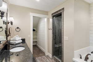 Full bathroom with a stall shower, a garden tub, vanity, wood finished floors, and a spacious closet