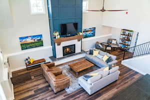 Living area featuring wood finished floors, a fireplace, a high ceiling, baseboards, and ceiling fan