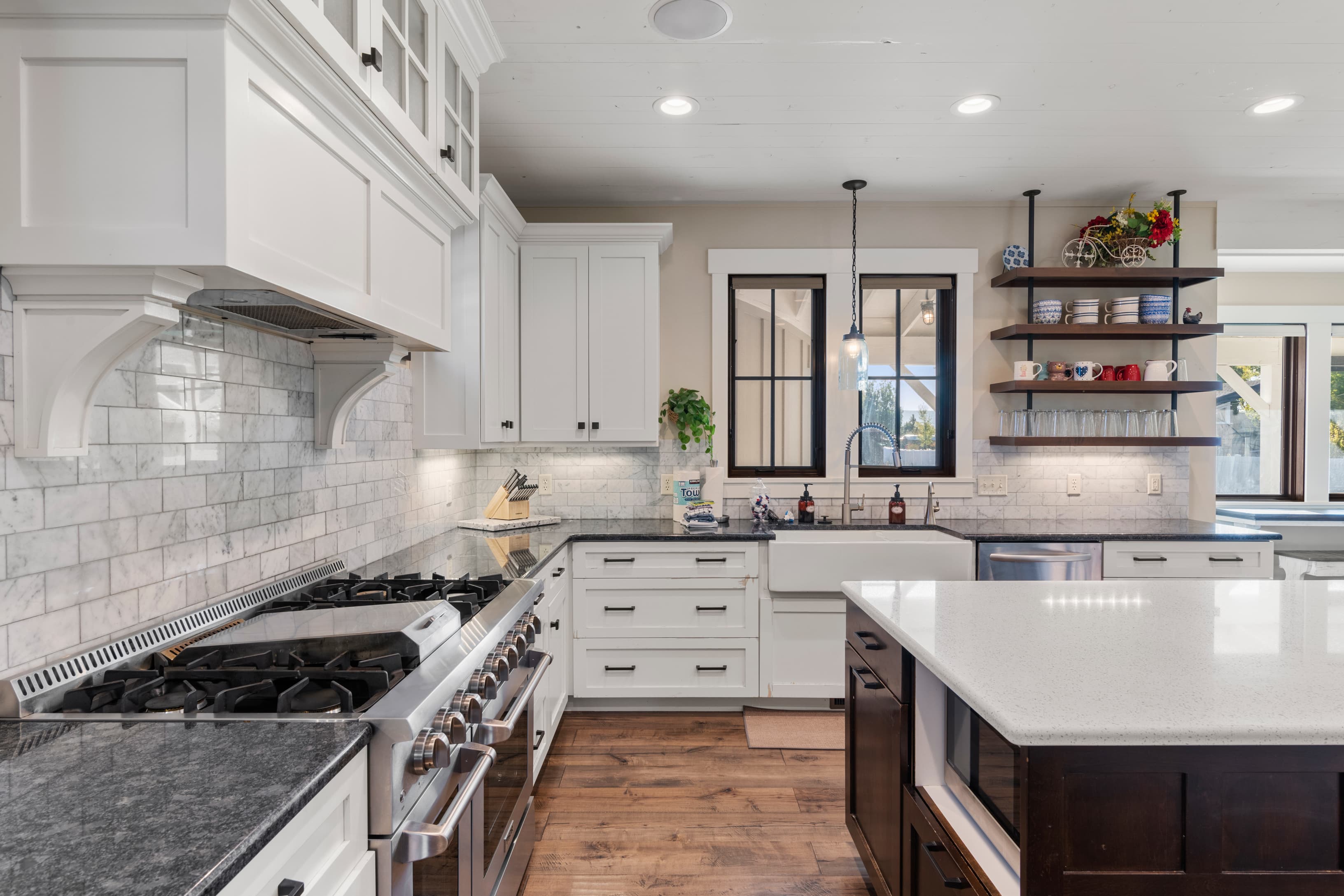 Kitchen with stainless steel appliances, a sink, open shelves, tasteful backsplash, and white cabinetry