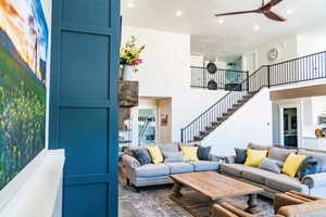 Living area featuring stairway, recessed lighting, a ceiling fan, and a high ceiling