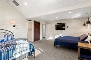 Bedroom with a barn door, wooden walls, carpet flooring, recessed lighting, and lofted ceiling
