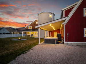 Back of property with a fire pit, a hot tub, and a patio area
