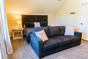 Carpeted bedroom with lofted ceiling and wood walls