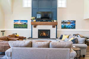 Living area featuring healthy amount of natural light, a stone fireplace, and wood finished floors