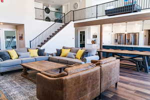 Living area featuring a towering ceiling, stairs, and dark wood finished floors
