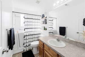 Full bathroom featuring toilet, vanity, and shower / bathtub combination with curtain