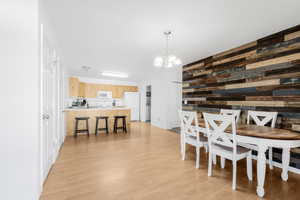 Dining area with wood walls, a chandelier, and light wood-type flooring