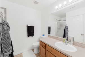 Full bathroom featuring vanity, a stall shower, toilet, and baseboards