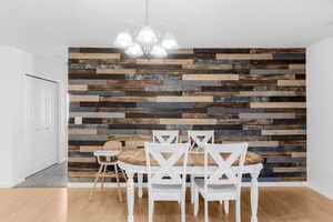 Dining space featuring wooden walls, a chandelier, wood finished floors, and baseboards