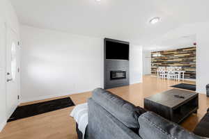 Living room with wood finished floors, vaulted ceiling, a fireplace, and baseboards