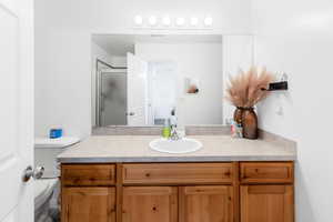 Full bath with vanity, toilet, and a stall shower